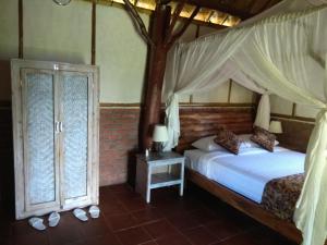 PenebelBali mountain forest cabin的一间卧室配有一张带天蓬的床和两个窗户。