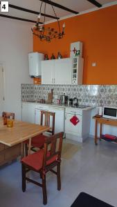Trafaria福戈度假屋的厨房配有白色橱柜和一张带椅子的木桌