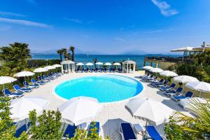 代森扎诺-德尔加达利都国际酒店的一个带椅子和遮阳伞的游泳池以及大海
