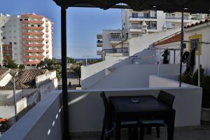 蒙蒂戈杜Casa Da Praia "AL"的阳台上配有一张黑色的桌子和椅子,阳台配有遮阳伞