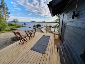 LeppälahtiKesämökki Tanela的海滩上带椅子和桌子的木制甲板