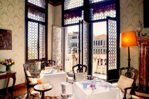 威尼斯大运河皮萨尼宫酒店的一间带桌椅的用餐室和窗户。