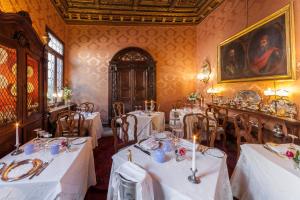 威尼斯大运河皮萨尼宫酒店的一间用餐室,配有白色的桌椅和绘画作品