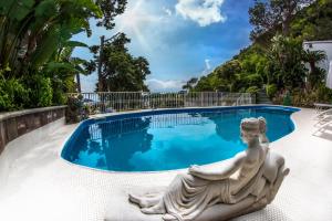 伊斯基亚Ischia Dream Visions的雕像坐在游泳池前