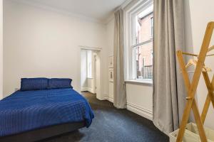 但尼丁The Stuart Street Terraced House的一间卧室设有蓝色的床和窗户。