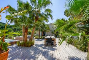 圣特罗佩villa Sant-Anna的木甲板,配有桌子和棕榈树