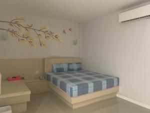 Ban Khlong Ta KhotMerry Resort Photaram的卧室配有一张床,墙上挂有绘画作品
