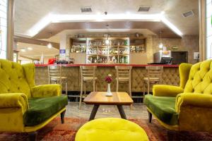 韦林格勒巴尔尼奥Spa水疗酒店的酒吧设有绿色椅子、桌子和柜台