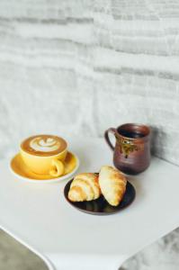 乌隆他尼维尔德豪华青旅的桌上的咖啡和羊角面包