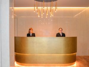 西尔米奥奈泰尔梅大酒店的两个女人站在大厅柜台后面