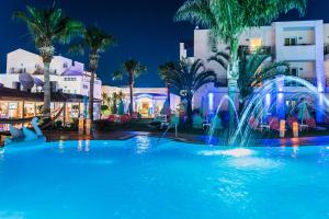 玛利亚Yiannis Manos Hotel Resort的游泳池在晚上设有喷泉