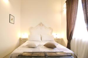 彼得拉桑塔La Piccola Atene的卧室配有白色的床、两张桌子和一扇窗户