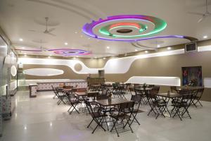 焦特布尔Shivam Palace & Resort的餐厅设有桌椅和色彩缤纷的天花板。