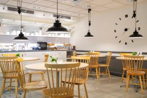 于默奥Hotell Vilja的餐厅设有桌椅和墙上的时钟