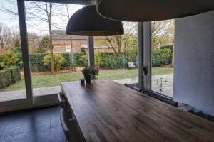 博克斯特尔Bed & Wellness Boxtel, luxe kamer met airco en eigen badkamer, ligbad的一间带木桌和大窗户的用餐室