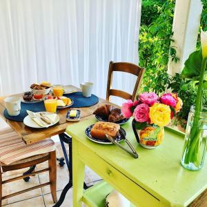 桑吉内Les Arums de Sanguinet的一张桌子,上面摆放着早餐食品和鲜花