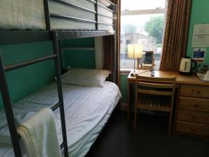 爱丁堡双狮酒店的一间卧室配有双层床、书桌和窗户。