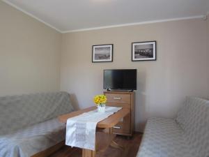 辛安诺泽蒂Manta Apartamenty的客厅配有两把椅子、一张桌子和一台电视