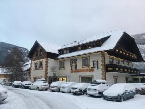 圣迈克尔隆高Landhaus Lungau的一座有雪盖的建筑,里面的汽车停在停车场