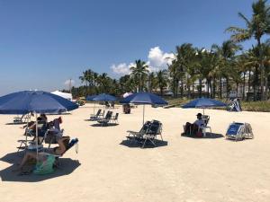 伯迪亚哥Flat com serviços na Riviera的一群人坐在海滩上,拿着遮阳伞