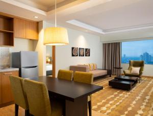 雅加达Holiday Inn & Suites Jakarta Gajah Mada, an IHG Hotel的厨房以及带桌椅的起居室。