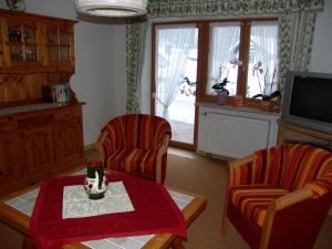 EngedeyHaus Alpenglühn的客厅配有两把椅子、一张桌子和电视