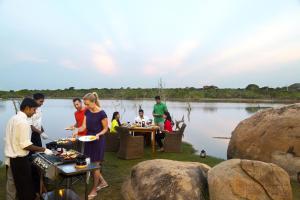 雅拉亚拉辛纳蒙野生酒店的一群人在水边的桌子上吃食物