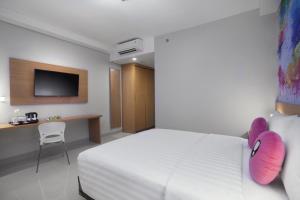 当格浪favehotel Hasyim Ashari Tangerang的酒店客房的床铺上配有粉红色的拖鞋