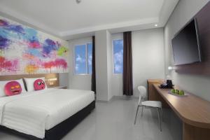 当格浪favehotel Hasyim Ashari Tangerang的酒店客房设有一张床、一张书桌和一台电视机。
