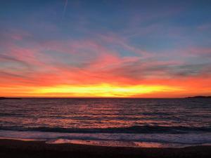 马赛LE CABANON BLEU SUR LA PLAGE的海滩上的日落与海洋