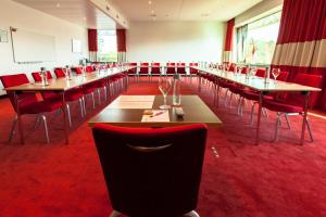 巴塞尔巴塞尔机场酒店 - 交通便利、热情友好的一间会议室,配有桌子和红色椅子