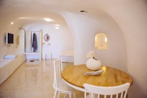 阿克罗蒂里SantoCaves的一间带木桌和白色椅子的用餐室
