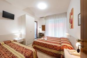 卡奥莱Hotel Stoccarda的酒店客房设有两张床和电视。