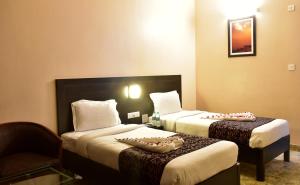 瓦拉纳西城市客栈酒店的酒店客房,配有两张床和椅子