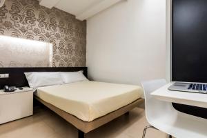 帕尔马萨伏伊酒店的一间卧室配有一张床和一张桌子上的笔记本电脑