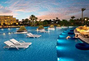 赫尔格达Steigenberger Aldau Beach Hotel的一个带椅子的度假游泳池和一个位于酒店后面的酒店