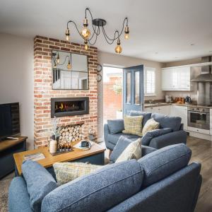 坎伯利Owlers Cottage的客厅设有2张蓝色的沙发和砖墙