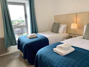 格拉斯哥Principal Apartments - Clyde Waterfront Apartments的一间卧室配有两张带毛巾的床