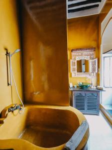 桑给巴尔科勒酒店的带浴缸的浴室,浴室拥有黄色的墙壁