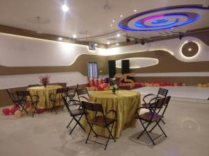 焦特布尔Shivam Palace & Resort的宴会厅设有2张桌子和椅子,拥有大型天花板