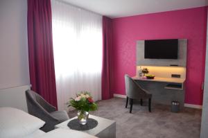 霍鲁梅尔希尔Hotel Garni Nordseejuwel的酒店客房设有粉红色的墙壁和一张带电视的书桌。