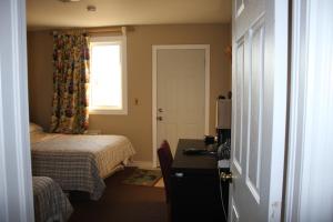 查塔姆肯特汽车旅馆的一间卧室配有一张床、一张书桌和一个窗户。