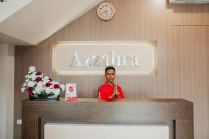 安汶Super OYO 1006 Azzahra Guest House Syariah的站在酒店房间柜台后面的人