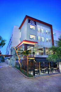三宝垄Hotel Neo Candi Simpang Lima - Semarang by ASTON的一座酒店大楼前面有棕榈树