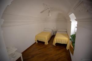 卡塔尼亚Sicily Luxury B&B的配有白色墙壁和木地板的客房内的两张床