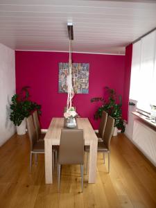 施瓦巴赫SC Apartment - Nürnberg Messe / Fränkisches Seenland的用餐室设有木桌和粉红色的墙壁。