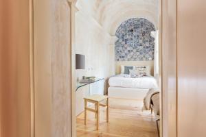 里斯本Archi-Pelago Alfama Design Suites Guesthouse的一间卧室配有一张床和一张桌子及椅子