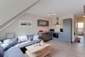 特拉森海德Muehlenidyll 2 _ Trassenheide的一间带蓝色沙发的客厅和一间厨房