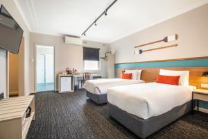 艾塔龙海滩Nightcap at Ocean Beach Hotel的酒店客房设有两张床和一台平面电视。