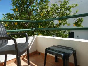 维拉诺瓦德卡塞拉My Second House的阳台上摆放着两把椅子和一张桌子,阳台上种着橘子树